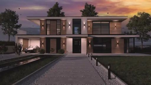 Exteriör frontvy av modern villa i skymning med fasadbelysning och varm himmel.