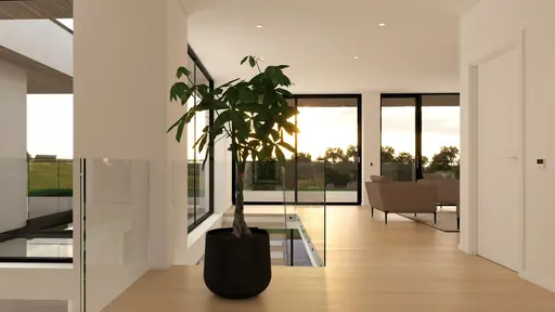 Interiör hall med stora glaspartier, svart kruka med växt och kvällsljus.